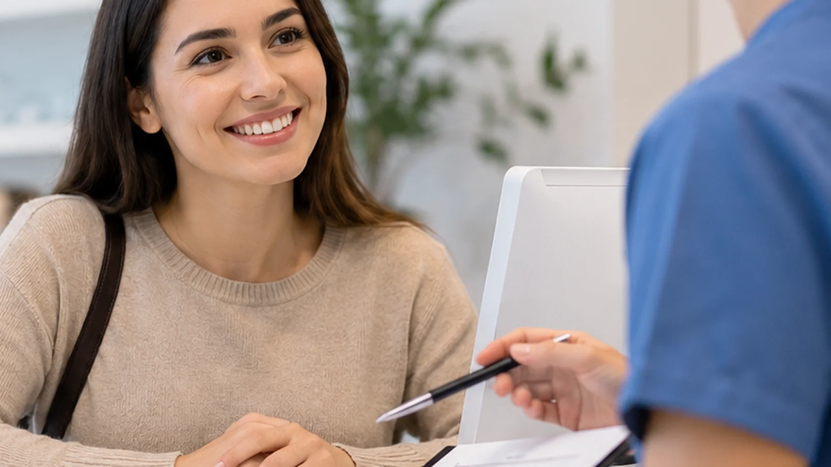 A patient listens to a clinic professional as they review documents about paying for dental treatment.